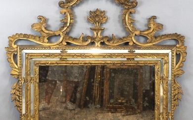 Specchiera di linea rettangolare in legno intagliato e dorato, ricca cimasa traforata da cui si dipartono volute e tralci fogliacei, altezza cm. 130x112