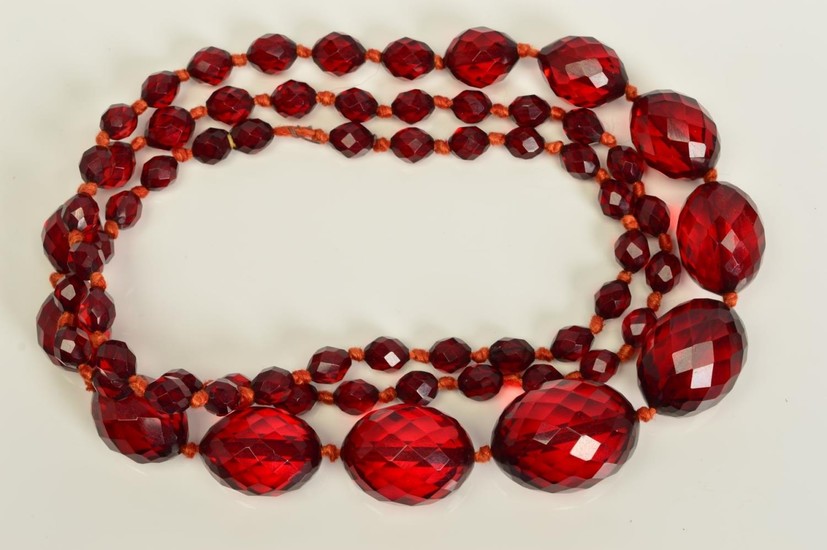A FACETED RED PLASTIC BEAD NECKLACE, designed as a single ro...