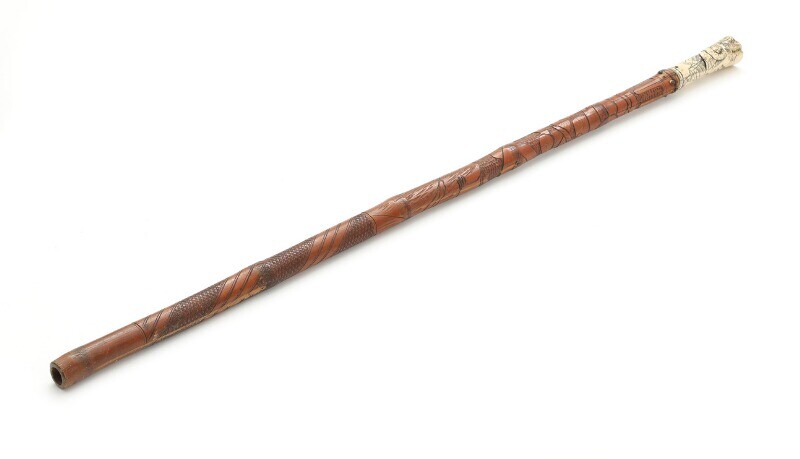 A Japanese bamboo walking stick with bone handle, carved with warrior and pine. Early 20th century. L. 86 cm.