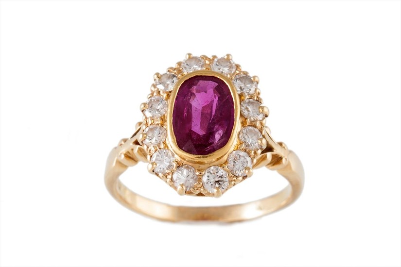 A RUBY AND DIAMOND CLUSTER RING, the oval ruby to a surround...