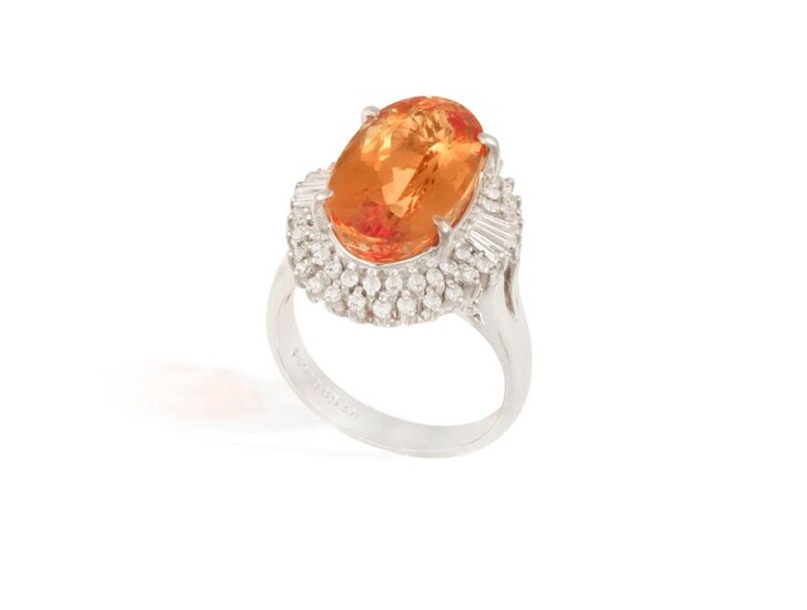 A TOPAZ AND DIAMOND CLUSTER RING The elongated oval-shaped topaz...