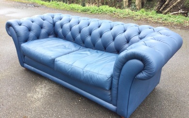 A leather button upholstered chesterfield sofa with loose cushions and...