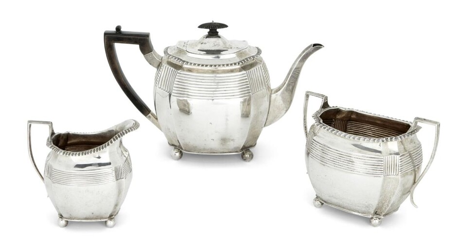 A matched Victorian silver three piece tea service, the sugar and milk London, 1895, Charles Stuart Harris, the teapot London, 1897, Thomas Bradbury & Sons, each raised on four ball feet and designed with reeded banding to body and gadrooned rims...