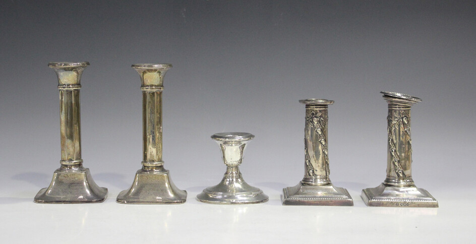 A pair of Edwardian silver candlesticks, each of cylindrical form, decorated in relief with spiralli