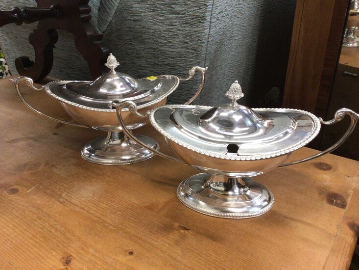 A pair of silver plate sauce tureens in the Adam style of oval form on a raised foor with gadroon border, swan handles and pineapple finial
