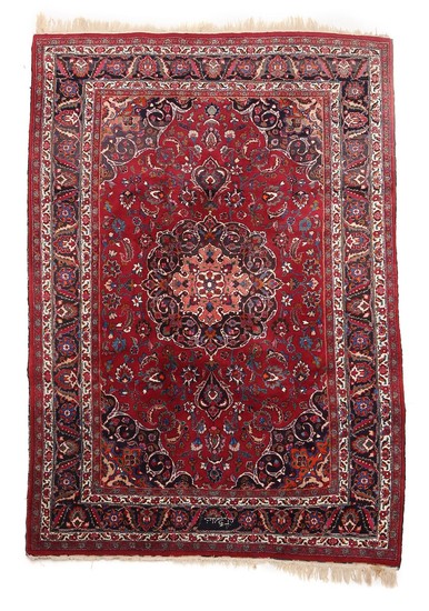 A signed Persian carpet, classical medallion design with entwined branches, ornaments, flowers and foliage on red base. 20th century. 312×205 cm.