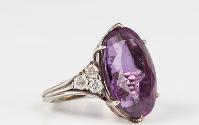 An amethyst and diamond ring, claw set with the large oval cut amethyst between circular cut diamond