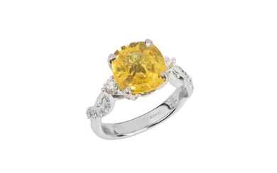 A yellow sapphire and diamond ring The cushion-shaped...