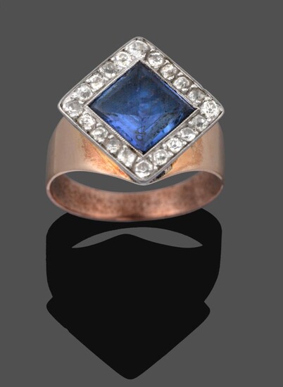 A Sapphire and Diamond Cluster Ring, the step cut sapphire orientated in a kite-shape within a...