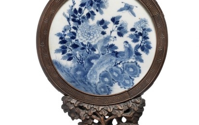 A circular Chinese porcelain plaque decorated in underglaze blue with peacock on rock and chrysanthemums. Qing, 19th century. Plaque diam. 21 cm.
