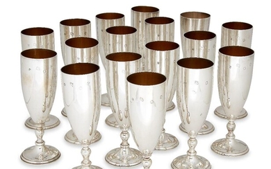 A matched set of sixteen Asprey & Co. silver champagne flutes, comprising nine examples hallmarked London, c.1974, five 1975 and two 1973, all designed with gilded interiors and plain bodies to short knopped stems, 18cm high, together with a silver...