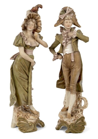 A pair of Royal Dux figures, 19th century, depicting a gallant and a young lady in green, beige and brown colour way, standing atop tree trunk bases with leaf and scrollwork decoration, triangle mark and pressnumbers 491 and 492 to underside, 36cm...