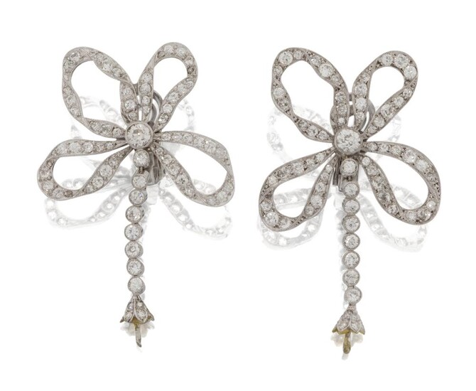 A pair of diamond earclips, each modelled as an old-brilliant-cut diamond set ribbon bow, suspending a diamond articulated line drop, with cusp mount terminals, (terminal stones deficient), c.1930, later clip and post fittings, approx. length 5.0cm...