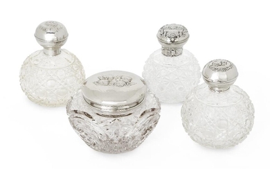 Four putti-decorated silver mounted glass vanity vessels comprising: three globular glass bottles with hobnail patterned glass and silver caps, one London, 1896, William Comyns & Sons, with push-button hinged cap, 13cm high; the second Birmingham...