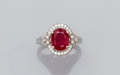 Ring in white gold, 750 MM, set with a treated ruby, oval, weighing 3.09 carats surrounded by diamonds between two palmettes with a diamond-covered pattern, size: 55, weight: 6.35gr. rough.