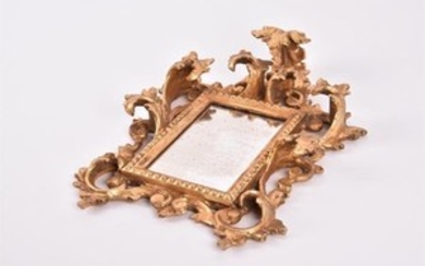 A small gilt gesso wall mirror with symmetrical scroll decoration to the border, the glass 13 cm x 8 cm.