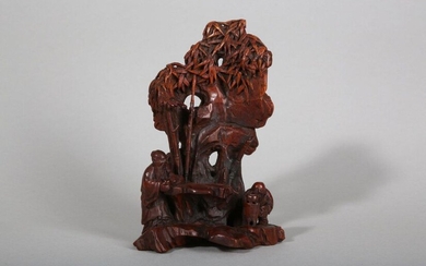 A CHINESE BAMBOO-ROOT 'SCHOLAR AND ATTENDANT' CARVING. Qing Dynasty. Carved from a section of bamboo root in the form of a standing scholar drinking tea and a crouching attendant boiling water, all beneath an overhanging rock and bamboo, 15cm H...
