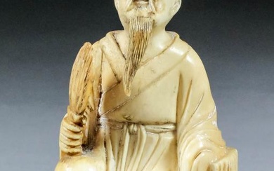 A Chinese carved ivory seated figure of a sage,...