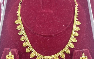 A South Asian unmarked yellow metal necklace with matching...