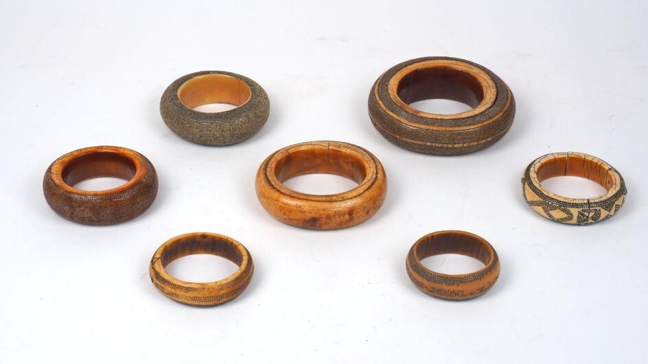 A group of large mixed African ivory bangles, 19th century, of varying patinas and sizes, some with additional decoration and various traditional repairs, one has additional metal terminals, bound with leather, approx. 11cm diameter (3)