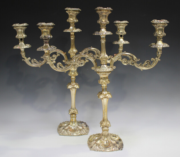 A pair of Edwardian silver twin-branch three-light candelabra, each foliate scroll branch with urn s