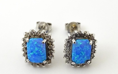 A pair of white metal stud earrings set with central opal bo...
