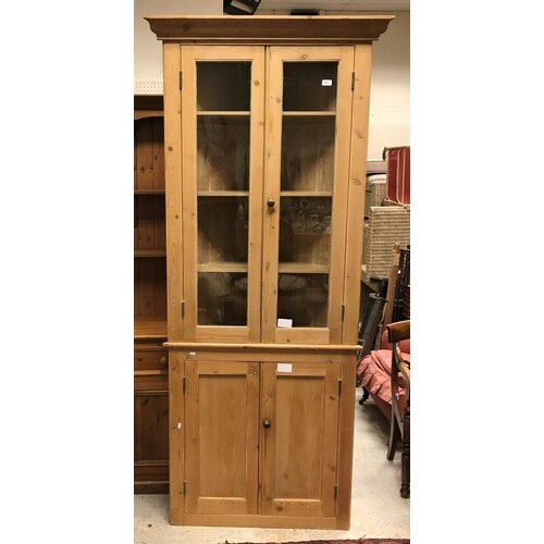 A pine freestanding corner cupboard with two glazed doors en...