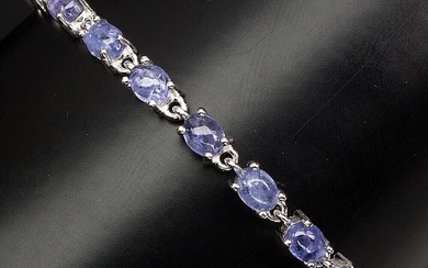 A tanzanite bracelet set with numerous oval-cut tanzanites, mounted in rhodium plated sterling silver. Adjustable length.