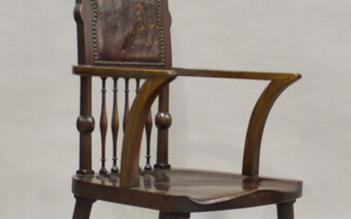 An Edwardian Arts and Crafts mahogany armchair by James Shoolbred & Co, the carved foliate top a