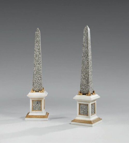 Pair of obelisks in granite and white marble, chased and gilded bronze ornamentation, with sphinx decoration.