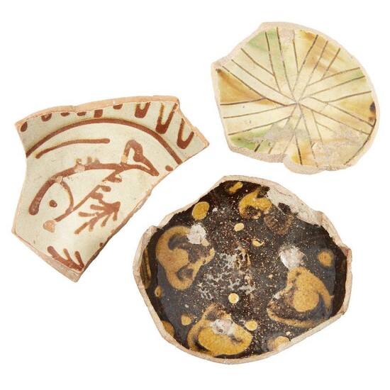 Three large Byzantine glazed pottery fragments, 10th-13th century, the first with a fish in raised red on a cream ground, the second with radial design in ochre and green and the third with yellow splashes on a dark brown ground, largest 15cm...