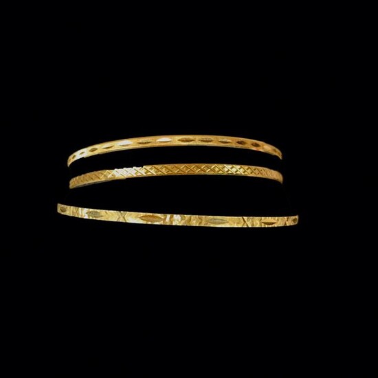 A CHARGED Three 18K (750°/°°) yellow gold bracelets chased with geometric motifs.