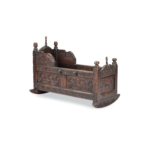A Charles II carved oak cradle With turned finials and carve...