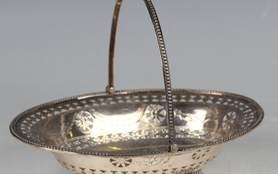 A George III silver oval bonbon basket with beaded swing handle above a pierced floral medallion and
