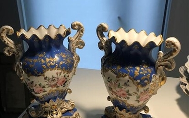 A pair of Paris porcelain vases on a base with polychrome decoration of flowers on a blue background. The neck is sinuous, the handles in acanthus leaf, the base with shell.H : 26,5 cm