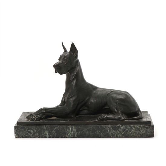 A patinated bronze sculpture of a reclining Grand Danois. Signed F. Diller. Mounted on a green marble. 20th century. L. 32 cm.