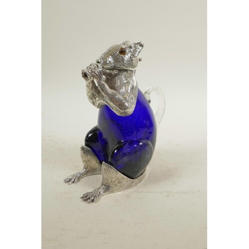 A silver plated and blue glass claret jug in the form of a s...