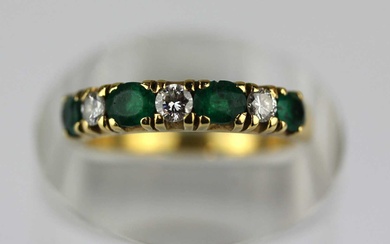 An 18ct gold emerald and diamond seven stone half eternity ring