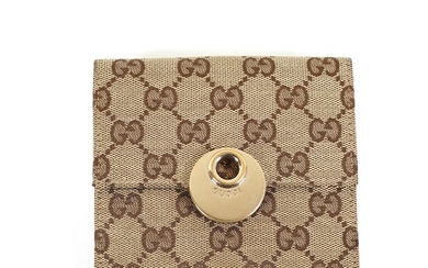 NOT SOLD. Gucci: A "Hook Folio Wallet" of beige golden monogram canvas with a coin...