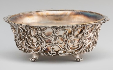 HOWARD & CO. STERLING SILVER BASKET Pierced body with rococo-style design of rocaille and blossoms. Four scrolling feet. Underside m...