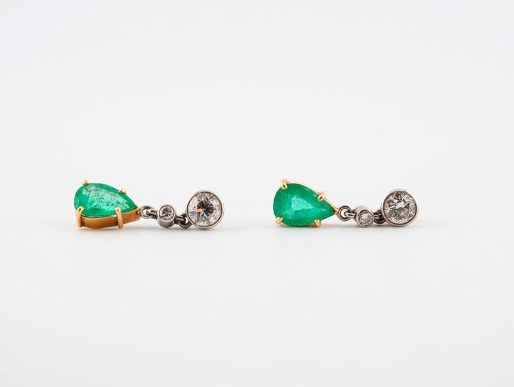 Pair of yellow gold (750) and platinum (850) earrings adorned with two brilliant-cut diamonds in a closed setting and holding a drop-cut emerald in pendulum shape.
