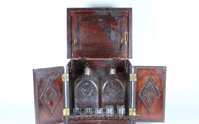 Piccolo mobile bar in legno tinto, scolpito e inciso a due sportelli , contenente dodici porta bicchieri e due bottiglie…