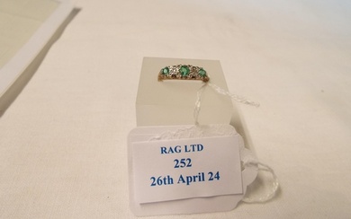 A 9ct gold half eternity ring inset with emeralds flanked by...
