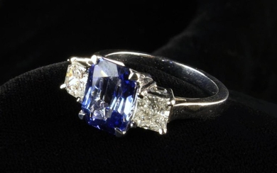 A Fine Sapphire & Diamond Ring. The 4.5 carat princess cut blue Ceylon sapphire flanked by princess