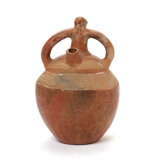 A Pre-Columbian fired clay vessel with stirrup handle. Circa 700–1200. H. 27.5 cm.