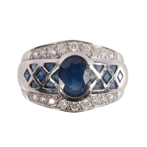 A SAPPHIRE AND DIAMOND DRESS RING the oval-cut sapphire flan...