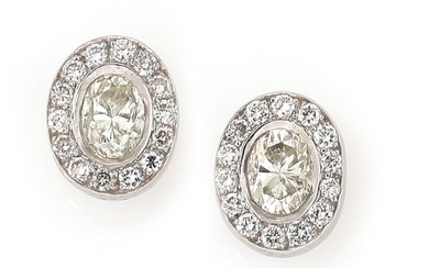 A pair of diamond ear studs each set with an oval-cut diamond...
