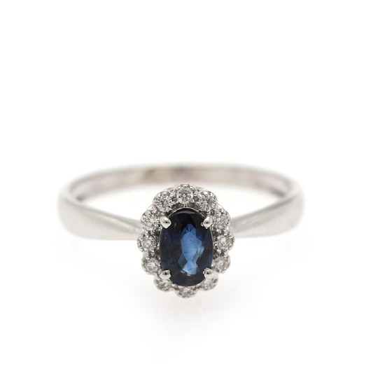 A ring set with an oval-cut sapphire weighing app. 0.62 ct. encircled by numerous diamonds weighing app. 0.11 ct., mounted in 18k white gold. Size 54.