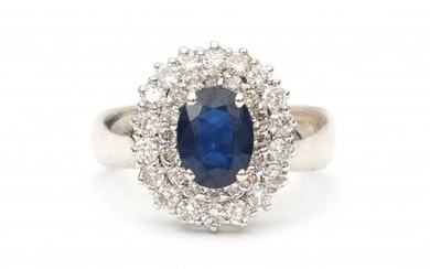 An 18 carat white gold diamond and sapphire cluster ring. Set with an oval faceted cut sapphire surrounded by thirty four brilliant cut diamonds, ca. 0.52 ct. in total, ca. F-G, VS2. Gross weight: 4.7 g.