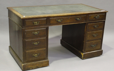 An Edwardian oak twin pedestal desk, the top inset with tooled leather above an arrangement of drawe
